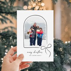 a person holding up a christmas card with an image of two children in the background