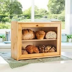 a wooden box filled with bread sitting on top of a table next to a window