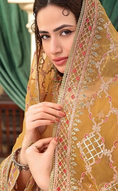 a beautiful woman in a yellow dress with an intricate shawl on her head and hands