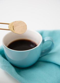 a cup of coffee with two wooden spoons sticking out of it's side