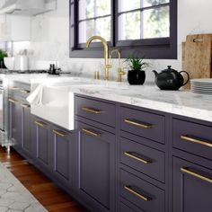 a kitchen with marble counter tops and purple cabinets, gold handles on the faucets