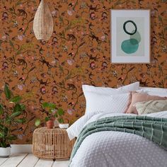 a bed room with a neatly made bed next to a wallpaper covered in flowers