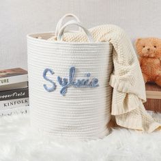 a white basket with the word style on it next to some books and a teddy bear