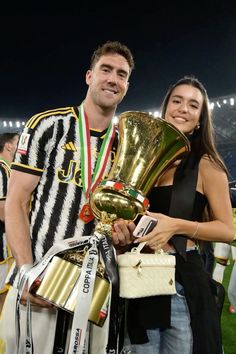 a man and woman standing next to each other holding trophies in front of a crowd