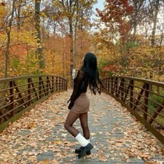 a woman is standing on a bridge in the fall leaves with her legs spread out