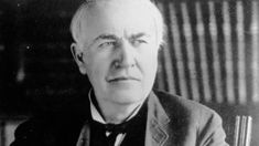 an old man wearing a suit and bow tie sitting in front of a chair with his eyes closed