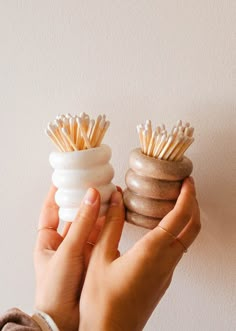 a person holding two small toothbrush holders in their hands