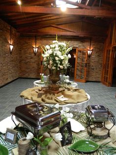 an arrangement of flowers and other items on a table in a room with brick walls