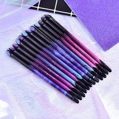 purple and black makeup brushes lined up on a white towel next to a triangle shaped object