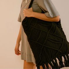 a woman carrying a black knitted bag