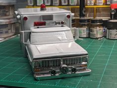 a toy police car sitting on top of a green table next to cans of paint