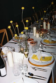 a table set with place settings and flowers in vases on the top, along with empty plates