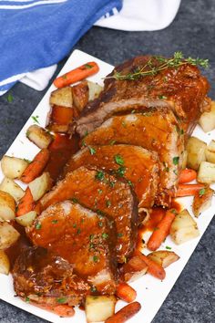 a white plate topped with meat and veggies on top of a table next to a blue towel