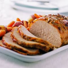 a white plate topped with sliced meat and veggies on top of a table