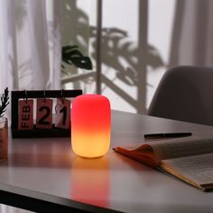 a lit candle sitting on top of a table next to an open book and pen