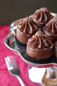 chocolate cupcakes with frosting on a silver platter next to a fork