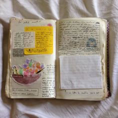 an open book with writing and pictures on the pages is laying on a white sheet