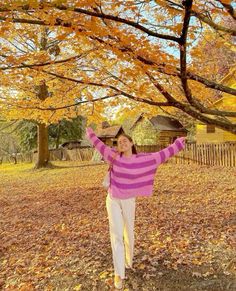 a woman standing under a tree with her arms in the air