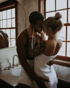 a man and woman standing in front of a bathroom mirror while talking on the phone