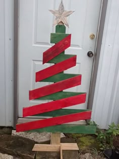 a christmas tree made out of strips of red and green wood sitting in front of a door