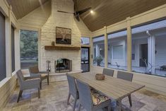 a dining room table with chairs and a fire place in the middle of an enclosed patio