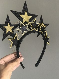 a hand holding a black headband with gold stars on it