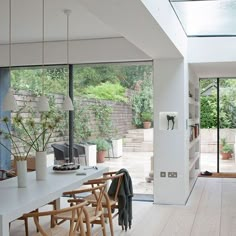 an open living room and dining area with large windows on both sides, white walls and wood flooring