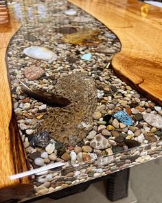 a wooden table topped with lots of rocks and gravel next to a glass top bench