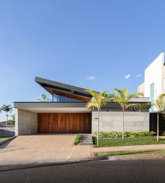 a modern house with palm trees in the front yard and large garage on the other side