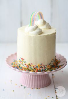 a cake on a pink plate with sprinkles and a rainbow topper