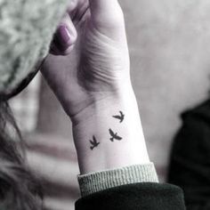 a woman's wrist tattoo with the word together written on her left hand and another person sitting in the background