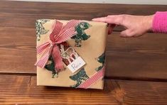 a person holding a wrapped present on top of a wooden table