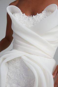 a woman in a white dress is holding her wedding dress