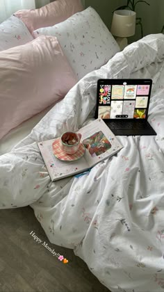 an open laptop computer sitting on top of a bed next to a cup of coffee