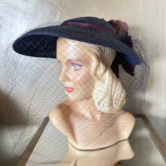 This Is An Outstanding Very Large Brim Navy Straw Hat From The Fabulous Fifties! The Round Crown Is Surrounded By A Very Large Brim Which Tapers Towards Then Back. Around The Crown There Is A Purple Shiny Band That Ties In A Bow At The Back. There Is Also A Large, Matching Purple Velvety Fabric "Rose" With Green Petals At The Center Back. A Huge Navy Veil Completes The Look. Stunning!!! Throughout The 1950s, Ladies Wore Hats Daily As A Part Of Their Attire As Was A Pair Of Gloves. Post War 1940’ Fabric Rose, Flower Band, Fabric Roses, Wide Brimmed Hats, Brim Hat, Fashion History, Wide Brimmed, Hats Vintage, Straw Hat