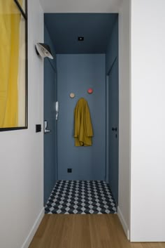 a blue hallway with black and white checkered flooring, yellow robe hanging on the wall