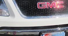 the front end of a white gmc truck with red lettering on it's grille