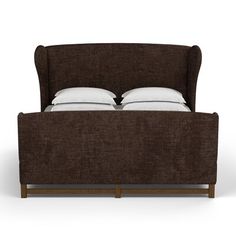 a bed with white pillows and brown headboard