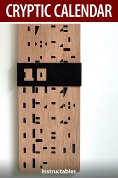 a wooden calendar with black and white squares on it, in front of a wall