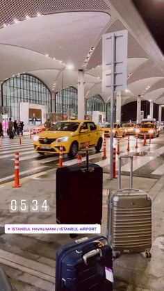 several pieces of luggage sitting on the ground in front of an airport terminal with yellow taxi cabs