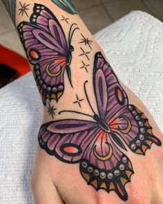 a hand with a purple butterfly tattoo on it