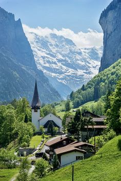 a church in the middle of a valley with mountains in the backgrouund