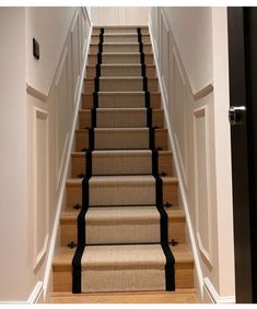 an open door leading up to a set of stairs with carpet on the bottom and black trim