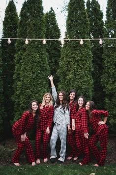 a group of women in red and black pajamas posing for a photo with their arms up