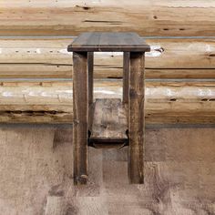 a small wooden table sitting on top of a hard wood floor next to a log wall