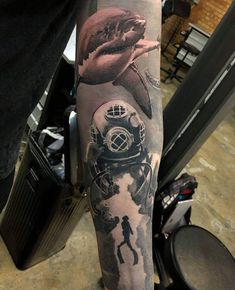 a man's arm with a shark and diving helmet on it