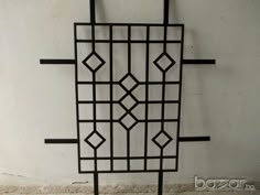 a black iron wall hanging on the side of a white wall with an intricate design