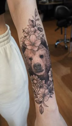 a woman's arm with a bear and flowers on it