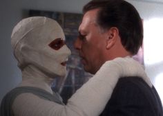 a man in a white mask hugging a woman with blood on her face and nose