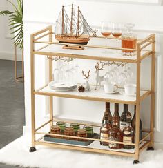 a bar cart filled with drinks and glasses on top of a white rug next to a potted plant